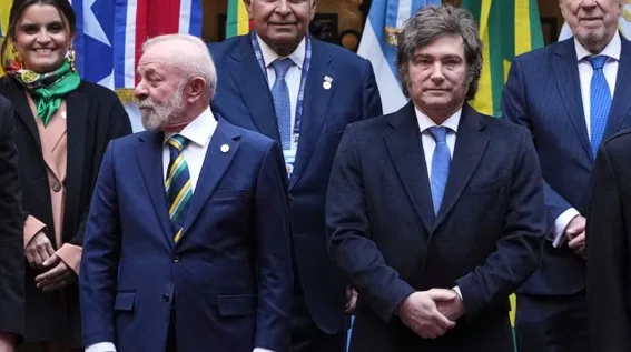 Javier Milei con traje en cumbre Mercosur rodeado de banderas de países miembros
