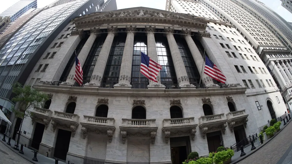 Pantallas de cotizaciones en Wall Street con gráficos en rojo y el logo de la Reserva Federal al fondo